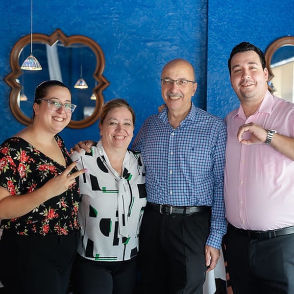 Four smiling Leila Restaurant staff members, two men and two women, pose together in front of a blue wall.