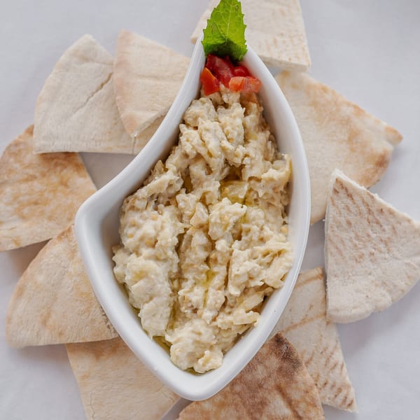 Leila Restaurant's creamy Middle-Eastern baba ghanoush, garnished with mint and tomato, surrounded by pita bread.